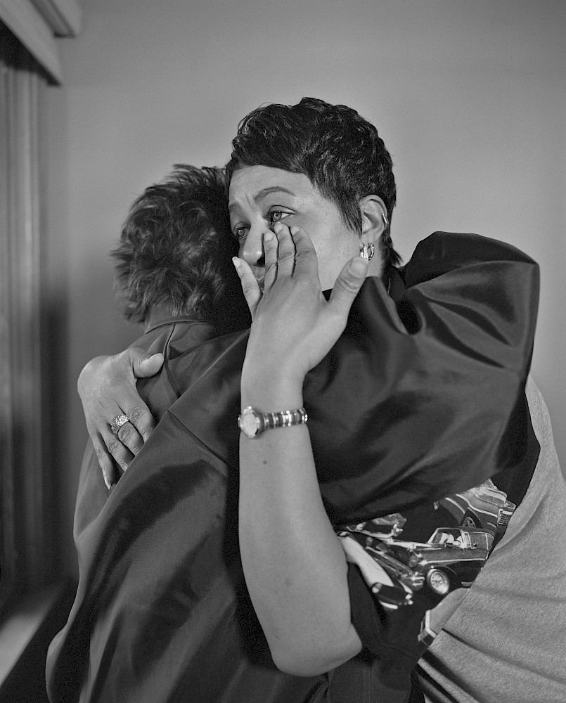 LaToya Ruby Frazier, Kesha Scales, UAW Local 1714, (22 years in at GM Lordstown Complex, Press Room), hugging her best friend and former co-worker Beverly Williams in her living room, Youngstown, OH, 2019  Gelatin silver print, 20 x 16 inches (50.8 x 40.6 cm) print © LaToya Ruby Frazier. Courtesy of the artist and Gladstone Gallery